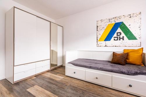 a white bedroom with a bed and a large mirror at Architektenwohnungen mit Panoramablick bei Köln in Lindlar
