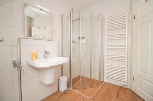 ein weißes Bad mit einem Waschbecken und einer Dusche in der Unterkunft Ferienwohnung Zeit zu Zweit Greetsiel in Greetsiel