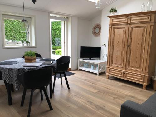 a living room with a table and chairs and a television at Huize Oostduin in Oostkapelle