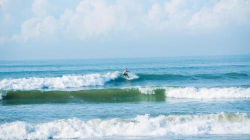 a person riding a wave on a surfboard in the ocean at Parangi Weligama Bay - Thema Collection in Weligama