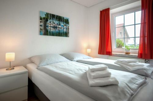 1 dormitorio con 2 camas y una ventana con cortinas rojas en Knusthof Lafrenz - Südwest, en Strukkamp auf Fehmarn