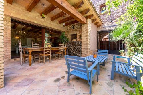 un patio con bancos azules y una mesa de madera. en Hauzify I Palauet del Remei, en Perelló