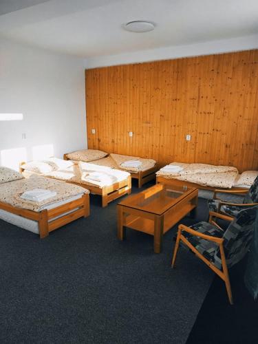 ŠkrdloviceにあるPenzion Vysočinaのベッド3台、テーブル、椅子が備わる客室です。