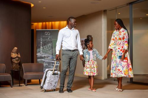 a man and a woman and a little girl holding hands at Noom Hotel Abidjan Plateau in Abidjan