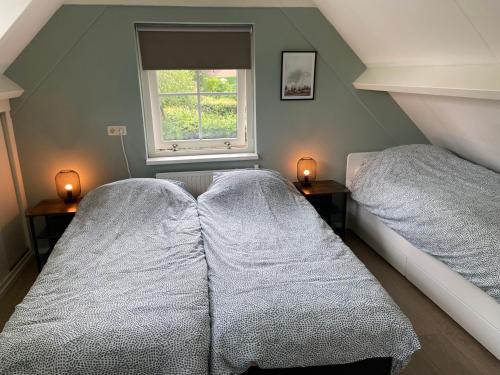 two beds in a room with a window at Bosboerderij de Veluwe, luxe huisje in het bos in Lunteren