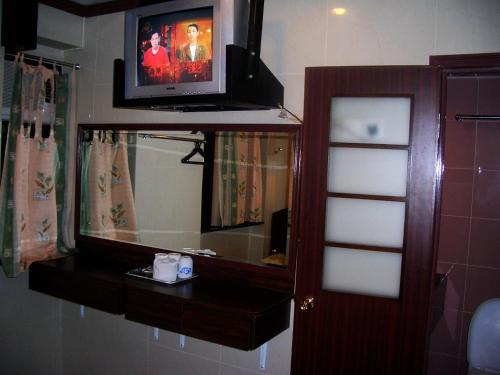 a bathroom with a mirror and a tv on the wall at Li’s Chain Hostel in Hong Kong