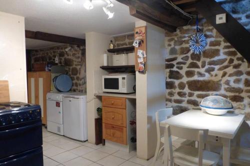 a kitchen with a white table and a stone wall at Les Deux Sabots in Bréel