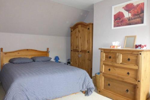 een slaapkamer met een bed en een houten dressoir bij Les Deux Sabots in Bréel