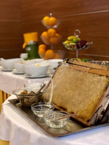 a table with a container of honey on a table with bowls of fruit at Aragosta Hotel in Durrës