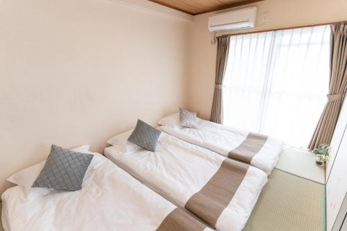 two beds in a room with a window at stay's ジローズ浄心 601号 名古屋 民泊 駅近 in Nagoya