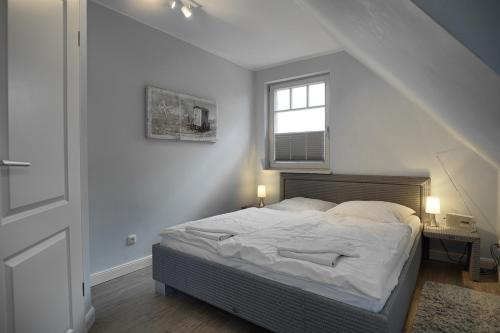 Dat suutsche Huus في زنغست: غرفة نوم بيضاء مع سرير مع نافذة