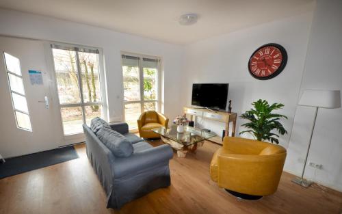 a living room with a couch and chairs and a clock at Ferienwohnungen Marienthal in Hamburg