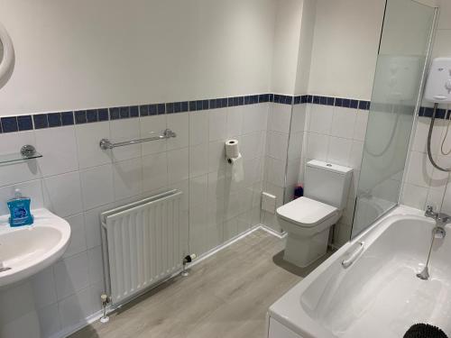 a bathroom with a tub and a toilet and a sink at Flat Two, 212 Eaglesham Road, East Kilbride, Glasgow in Glasgow