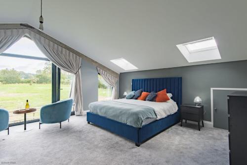a bedroom with a blue bed and a large window at Old Harrow Barn by Bloom Stays in Ashford