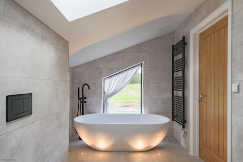 een badkamer met een bad en een raam bij Old Harrow Barn by Bloom Stays in Ashford
