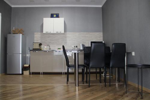 a kitchen with a table with black chairs and a refrigerator at Ann's Apartment in Tbilisi City