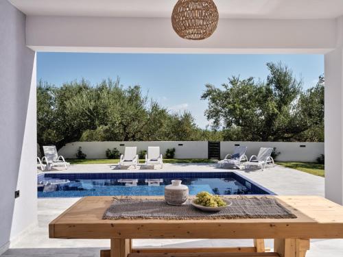 a patio with a table and a swimming pool at Kapodistria Luxury Villas - Serene Escape in a Scenic, Secluded Location, by ZanteWize in Plános