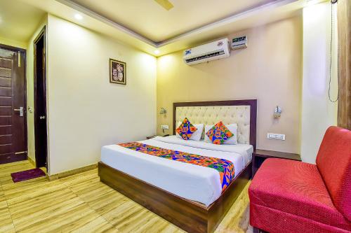 um quarto com uma cama e uma cadeira vermelha em Hotel Surya Residency em Dehradun