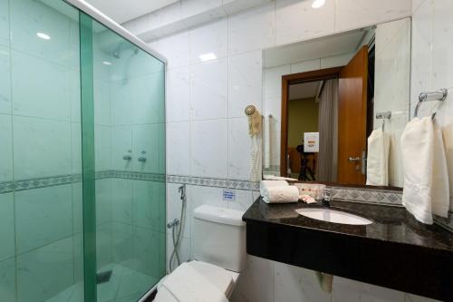 a bathroom with a glass shower and a toilet and a sink at Hotel Santorini in Vila Velha