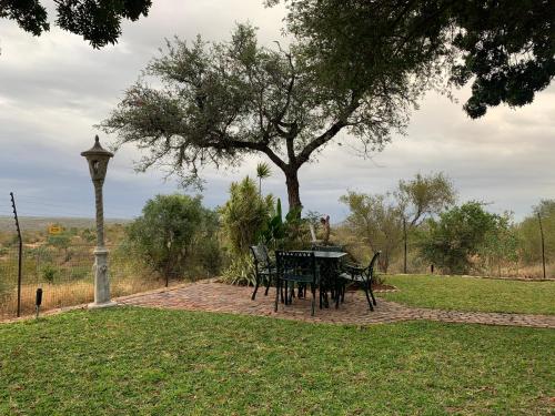 a table and chairs in a park with a tree at Modjadji Estate Lodge & Spa in Grietjie Nature Reserve