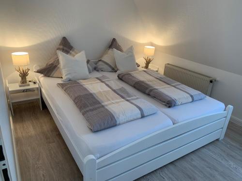 una camera da letto con un grande letto bianco con due lampade di FeWo Woge a Grödersby