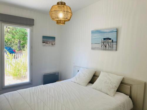 a bedroom with a bed with a window and a chandelier at Maison de la forêt, terrasse plein sud et standing in Saint-Jean-de-Monts