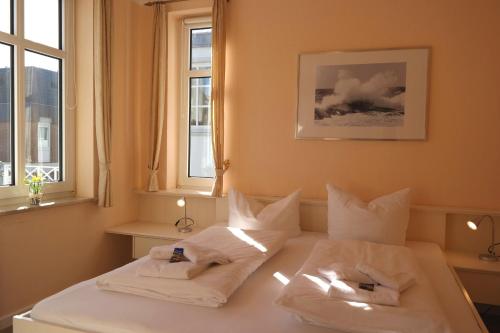 1 dormitorio con 2 camas y almohadas blancas en Haus Hansen - Wyk Whg 02, en Wyk auf Föhr