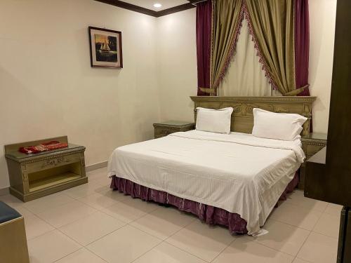 Schlafzimmer mit einem Bett mit weißer Bettwäsche und Kissen in der Unterkunft الشعلة للشقق المفروشة in Riad