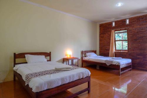 a bedroom with two beds and a window at Roemah Beong Syariah at Desa Wisata Kembanglimus Mitra RedDoorz in Magelang