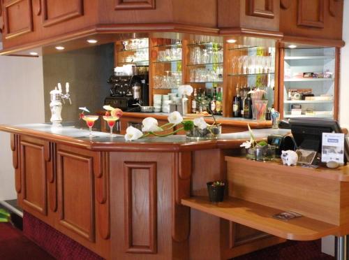 a bar with wooden cabinets and flowers on the counter at Auberge Du Cheval Blanc in Baud