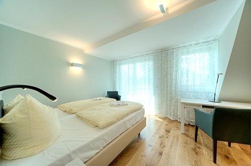 a bedroom with a bed and a desk and a window at MeerZeit - 21843 in Zingst