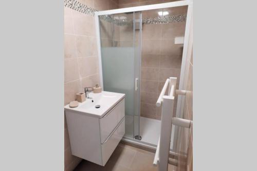 y baño con lavabo blanco y ducha. en Charmante maison cosy T2 avec terrasse en Tremblay En France