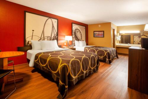 two beds in a hotel room with red walls at Super 8 by Wyndham Sandusky in Sandusky