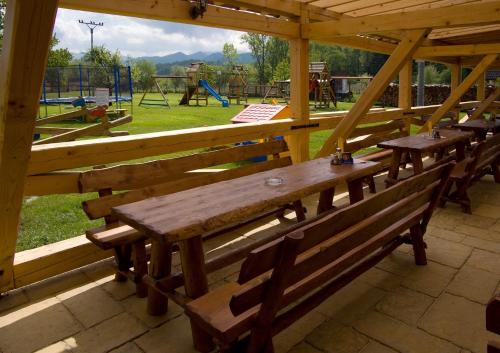 two wooden benches in a pavilion with a playground at Domčeky na Ranči in Sučany