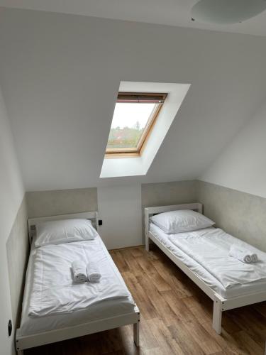 two beds in a room with a window at Penzion FAJN *** in Pardubice