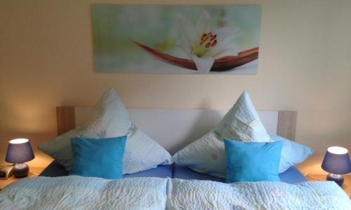 Un dormitorio con una cama con almohadas azules y una pintura en Ferienwohnung Voderberg Nr 1, en Burg auf Fehmarn