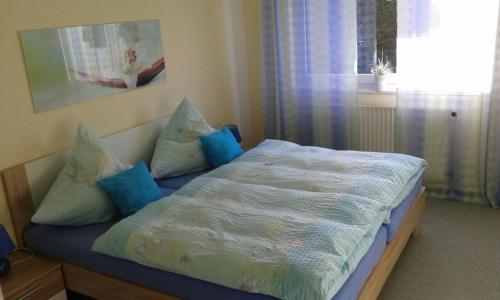 Un dormitorio con una cama con almohadas azules y una ventana en Ferienwohnung Voderberg Nr 1, en Burg auf Fehmarn