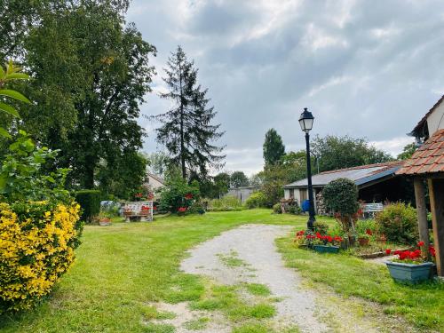 un chemin de terre dans une cour fleurie et éclairée dans l'établissement LES GITES DU JARIEL, à Jouy-sur-Morin