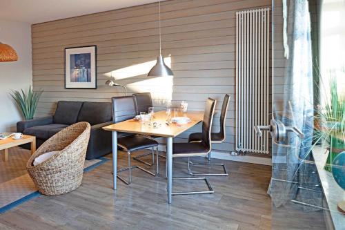 - une salle à manger avec une table, des chaises et un canapé dans l'établissement Pure Wonne Mandoe, à List auf Sylt