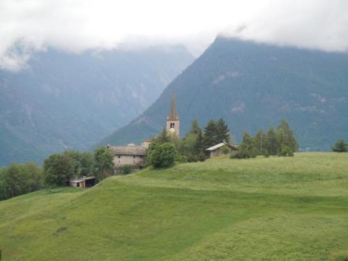 a church on top of a hill with a green field at Appartamenti Le Bistrot in Saint Nicolas