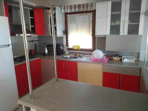 a kitchen with red cabinets and a sink and a window at Dikcati Pension in Şile