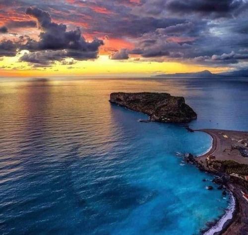 an island in the middle of the ocean with a sunset at IsolaDino b&b sweet home in Praia a Mare