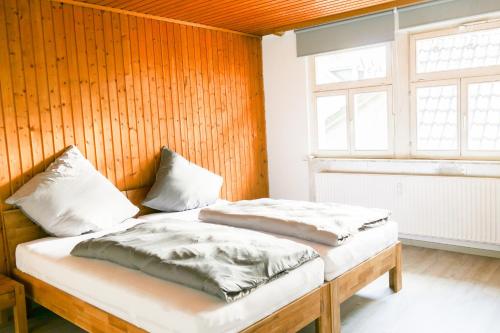 2 camas en una habitación con paredes de madera y ventana en Ferienwohnung Neu "Zum Westerwald" LAHN02, en Löhnberg