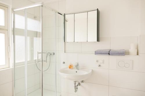 a white bathroom with a sink and a shower at Ferienwohnung Neu "Zum Westerwald" LAHN02 in Löhnberg