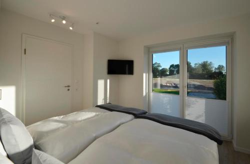 a white bed in a bedroom with a large window at Kopenhagen in Kronsgaard