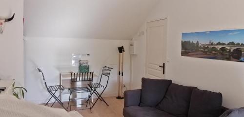 een woonkamer met een bank en een tafel en stoelen bij Charmante maisonnette in Orléans
