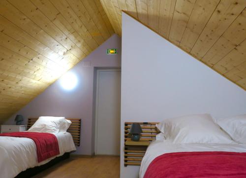 - une chambre avec deux lits et un plafond en bois dans l'établissement L'Ôberge, à Arlos