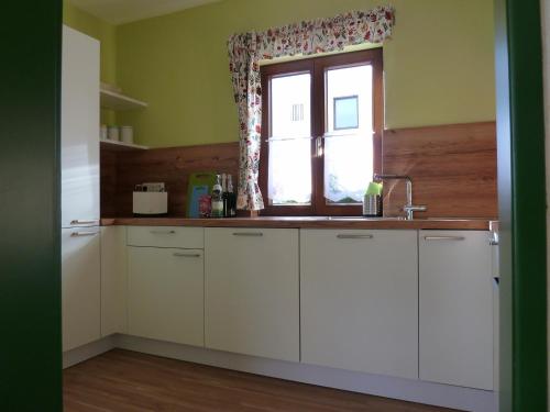 a kitchen with white cabinets and a window at Lina's Rhön in Bad Brückenau