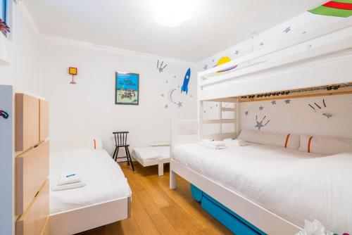 two beds in a room with white walls and wooden floors at Refurbished comfortable app 1min from the sea in Koksijde
