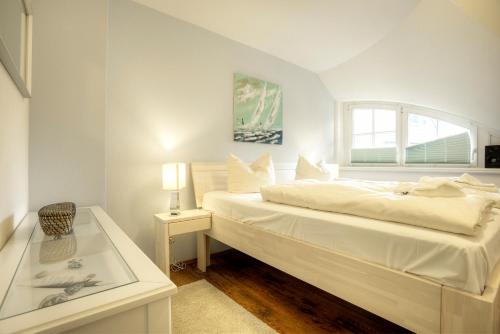 a white bedroom with a bed and a window at Haus Windflüchter in Zingst